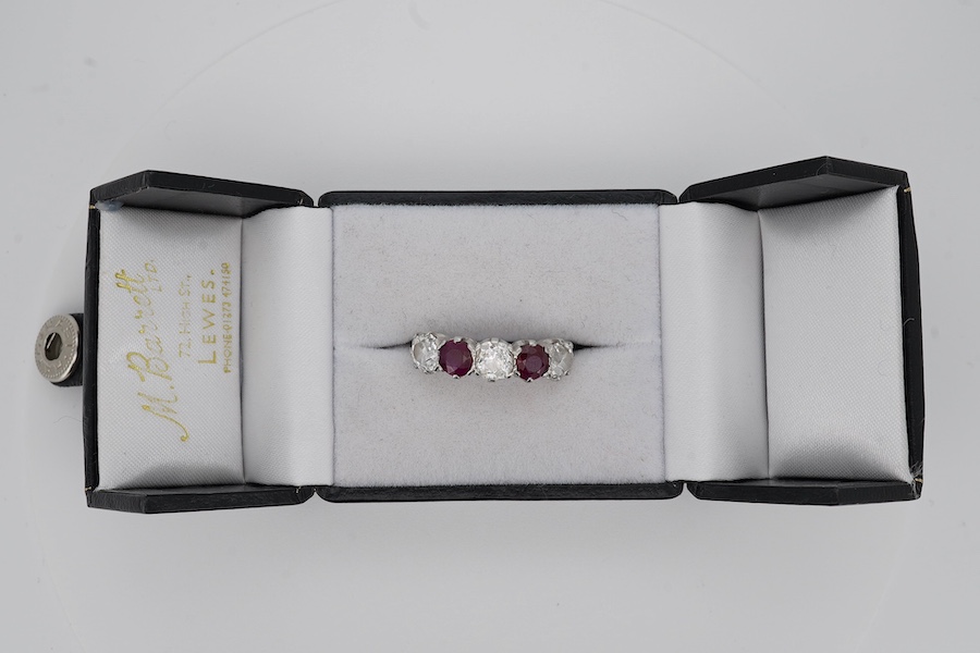 A ruby and diamond five-stone ring, set with an alternating sequence of antique cushion-shaped diamonds totalling approximately 1.50 carats, spaced with circular-cut rubies, mounted in platinum, size M (sizing beads), Br